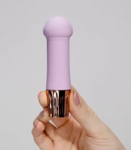 Mini vibrador mellow em silicone cor lavanda na mão demonstrando o tamanho compacto